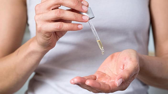 Žena si kvapká olej do dlaní